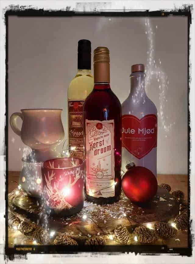 Kerst wijn en feestdecoratie met kerstballen, cranberry sap, en decoratieve kaarsen, perfect voor een gezellige kerstviering. Festive christmastime drinks and decor items voor een warme, feestelijke sfeer.