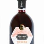 Aarzelende aandacht voor een fles Kinsale Mead Co. Wild Red Mead met een blackcurrant en kers smaak, bekroond met gouden medaille, ideaal voor liefhebbers van natuurlijke honingwijn.